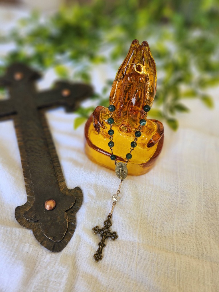 Single-decade rosary on praying hands