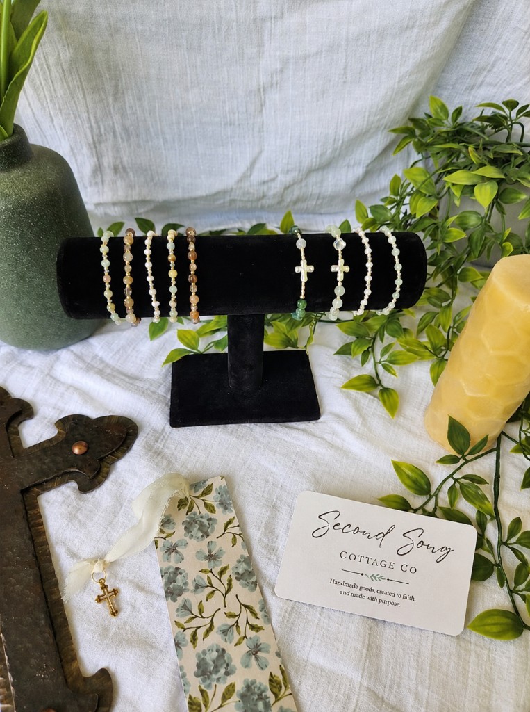 Studio table with beeswax candle, bracelets, and bookmark